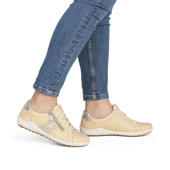 Pale yellow sneakers worn with blue jeans.