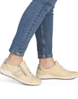 Pale yellow sneakers worn with blue jeans.