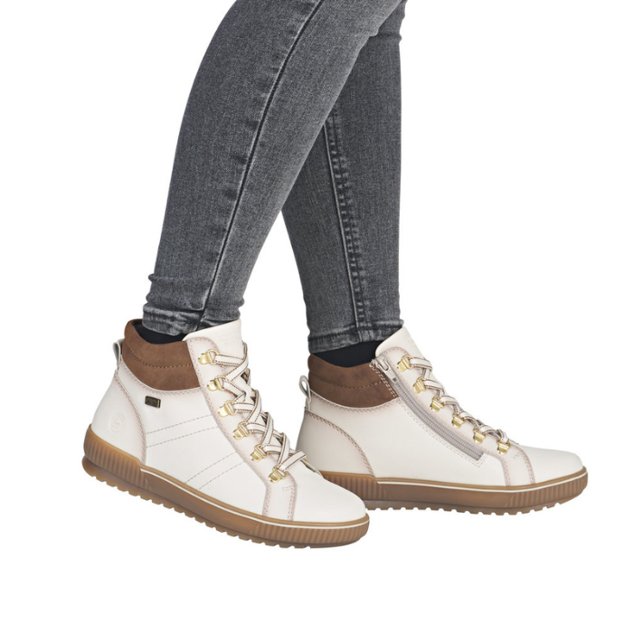 White high-top sneaker boots with brown accents worn with gray jeans.