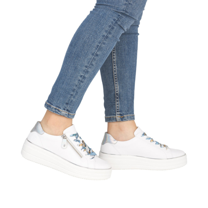 White sneakers with colorful laces worn with blue jeans.