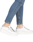 White sneakers with colorful laces worn with blue jeans.