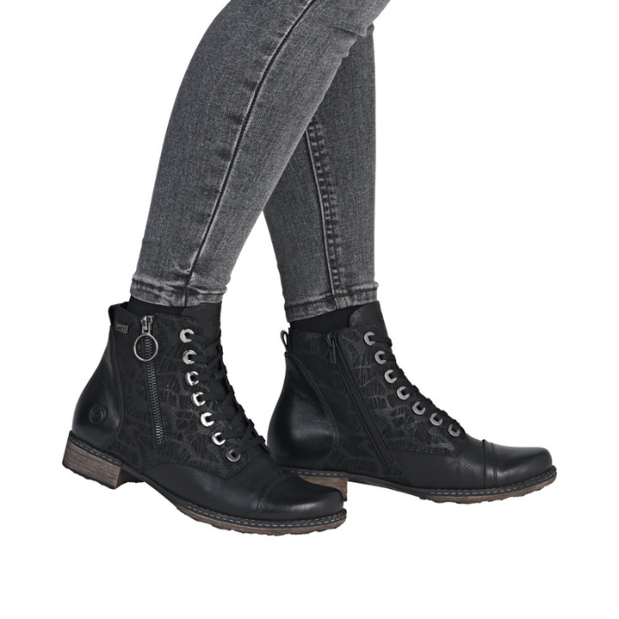 Black lace-up boots with side zipper worn with gray jeans.