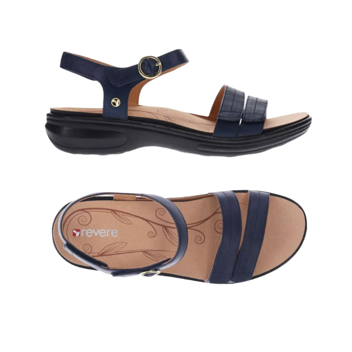 Pair of Navy strappy sandals with gold circle buckle detail, tan Revere logo'd footbed and black outsole.