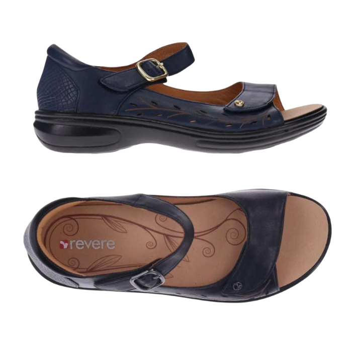 Pair of Navy blue floral perforated design on side of sandals with a gold buckle accent on Velcro strap, closed side and back, tan Revere logo'd footbed and black outsole.