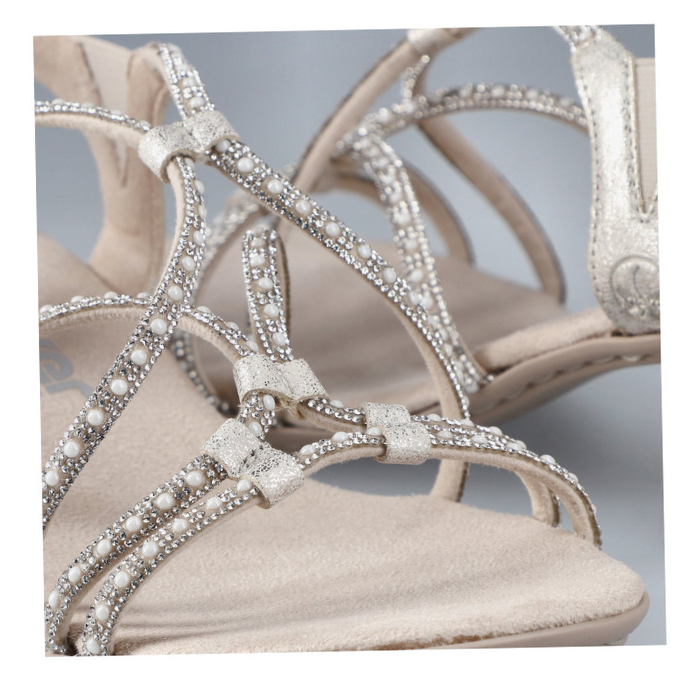 Close up of beige sandals straps showing diamonds and pearl details.