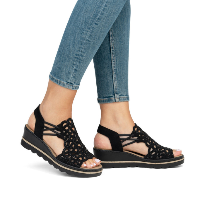 Black sparkly wedge sandals worn with blue jeans.