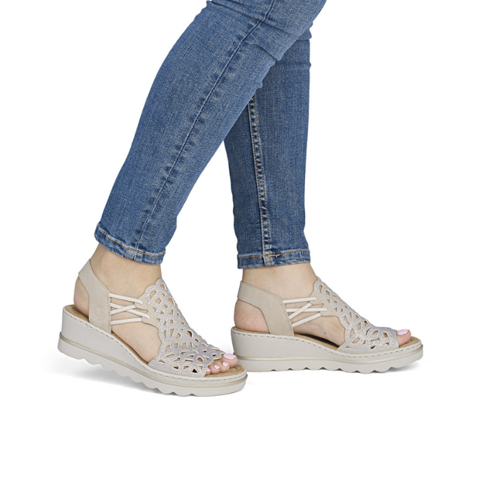 Beige sparkly wedge sandals worn with blue jeans
