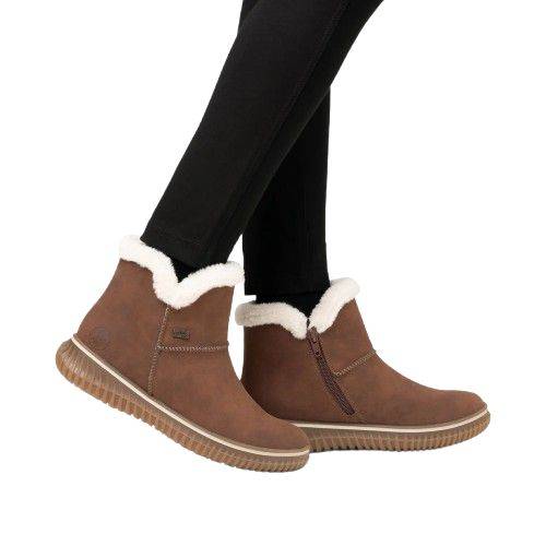 Model wearing Rieker 74260 women's ankle boots in brown, highlighting cozy faux fur collar and side zipper for easy winter wear.