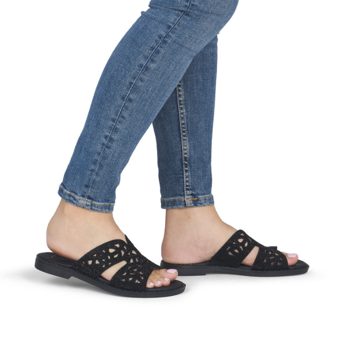 Black sparkly slide sandals worn with blue jeans.