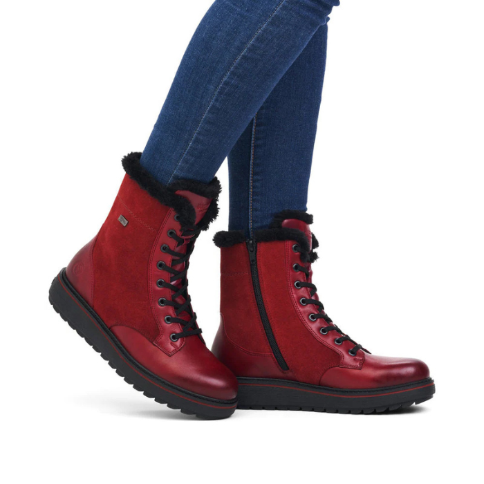 Red winter boots with fur trim worn with blue jeans.
