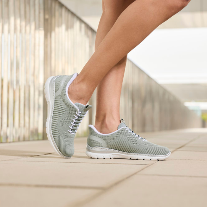 Person wearing light green sneakers on a blurred outdoor background
