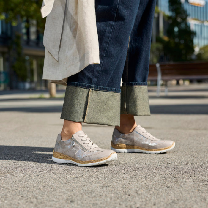 Person wearing shimmery beige sneakers on a city street with blurred background.