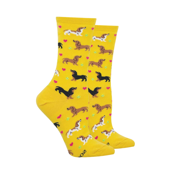 Pair of yellow socks with variety of dachshund colors playing with little hearts around them. 