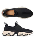 Pair of black slip-on sneakers with a mesh upper, tan footbed. white thick midsole and a black wave pattern rubber outsole.