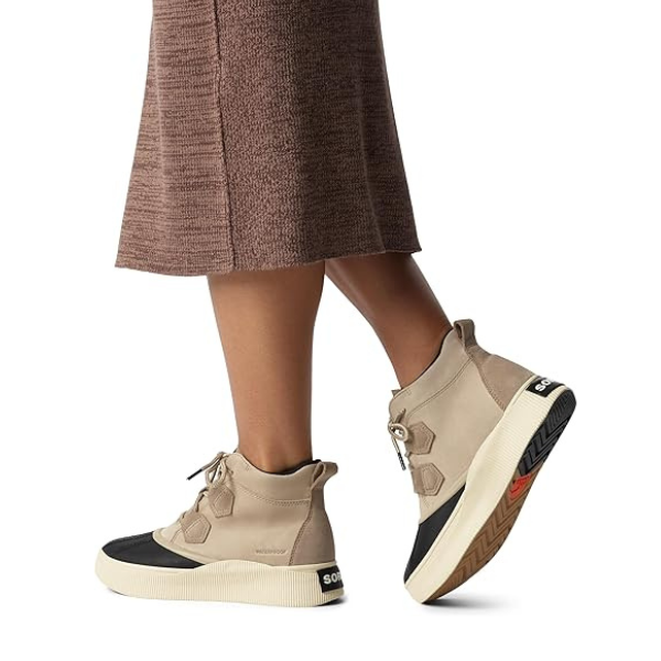 Model wearing taupe Sorel Out N About IV Classic waterproof boots with a skirt, highlighting versatile fall fashion footwear.
