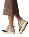 Model wearing taupe Sorel Out N About IV Classic waterproof boots with a skirt, highlighting versatile fall fashion footwear.