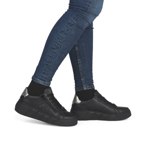 Black sneakers worn with blue jeans.