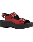Red sandal with a closed sides, open back, open toe, adjustable hook-and-loop with buckle accent straps across the top and around the ankle, and thick black platform outsole.