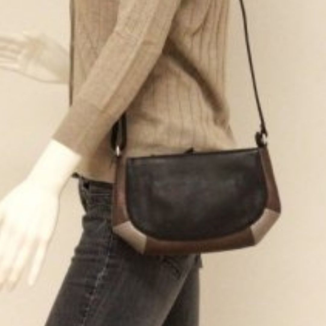 Women wearing black leather crossbody bag with silver and bronze leather trim