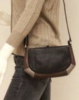 Women wearing black leather crossbody bag with silver and bronze leather trim