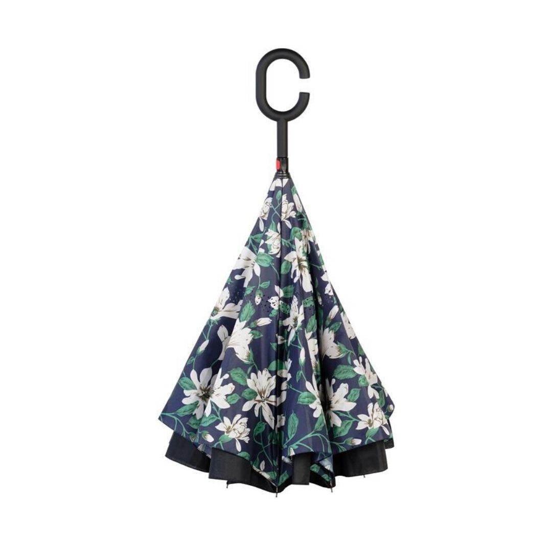 Closed Knirps reversible umbrella has c-shaped handle and white flower pattern on navy with green leaf design 