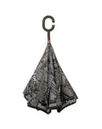Loosely closed Knirps reversible umbrella has c-shaped handle with newsprint article design