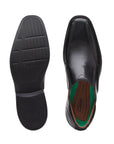 Top and bottom view of black leather bicycle toe slip-on shoe with black outsole. Clarks logo on center of insole.
