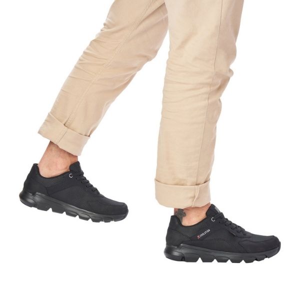 Man in beige pants wearing black R-Evolution lace-up sneakers.