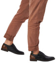 Man in brown pants wearing black leather dress shoes with laces and zipper closure.