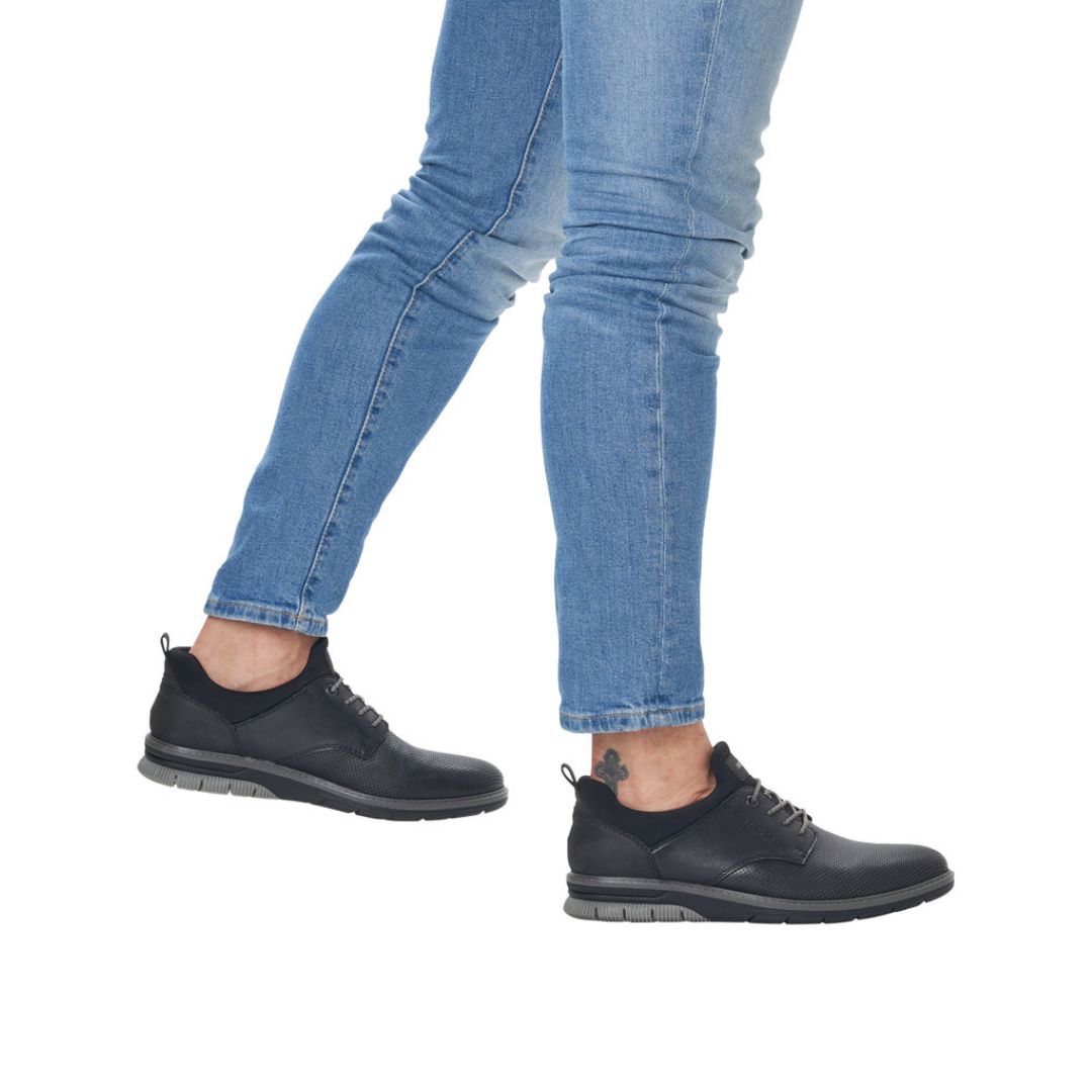 Black Men&#39;s Rieker 14450 Slip-On Lace Leather Sneakers paired with jeans, showcasing lightweight, stylish footwear for daily use.