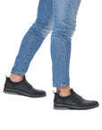 Man in jeans wearing black slip on sneakers with grey laces.