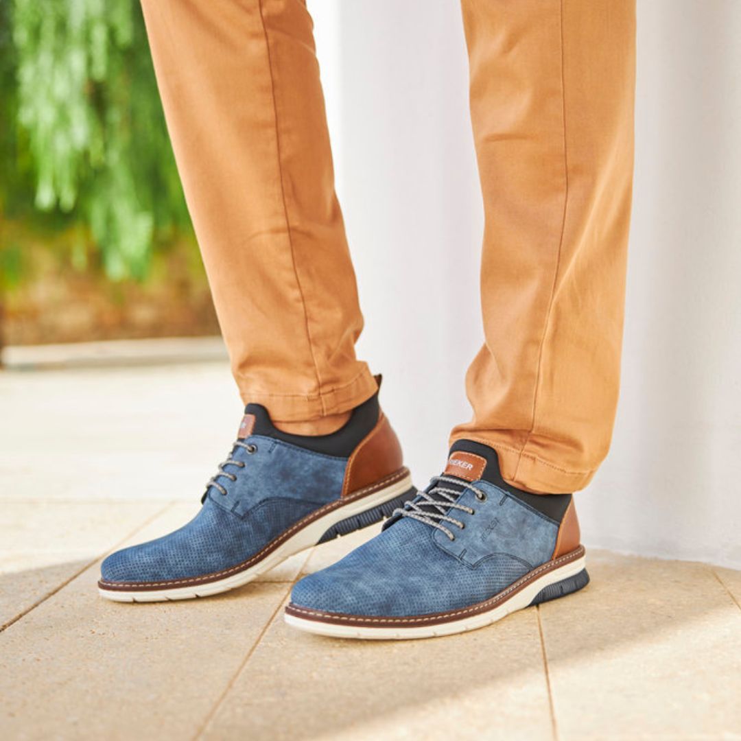 Man wearing brown pants and blue slip-on sneakers.