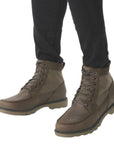 Man in black pants wearing brown lace up combat boot.