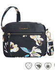 Black floral crossbody bag with gold Traelon emblem. Horizonal gold zipper is on the front.