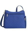 Blue quilted crossbody bag with horizontal zipper on rear exterior. 