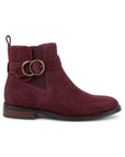 Burgundy suede ankle boot with brass circle buckles and low stacked heel.