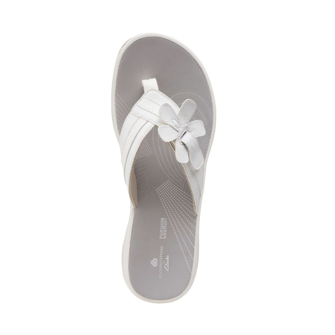 Top view of white flip flop with floral detail on strap. Clarks logo in white on insole.