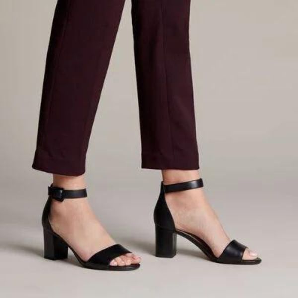 Women in purple pants wearing black leather heeled dress sandal with adjustable ankle strap.