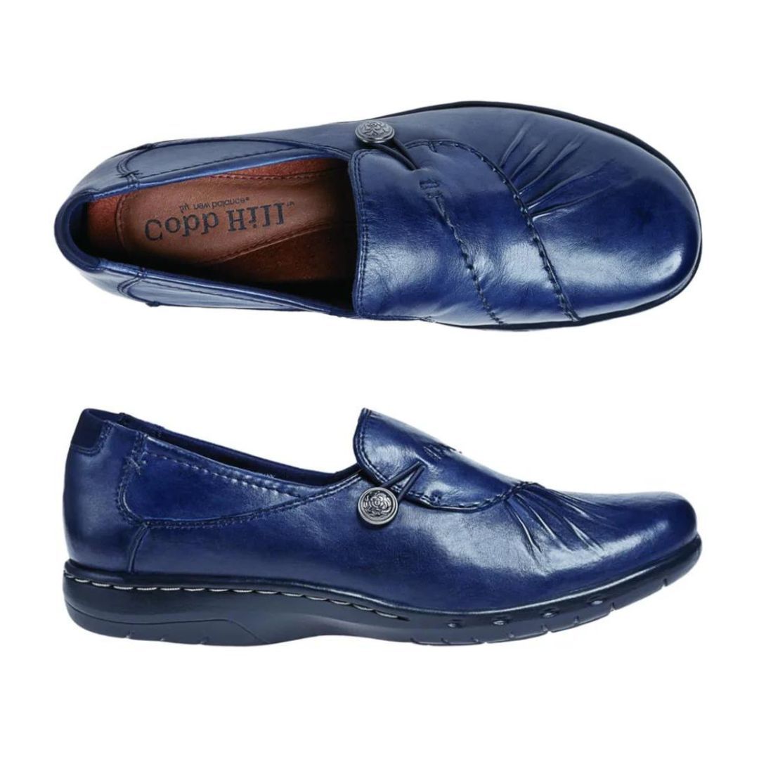 Top and side view of navy slip on shoe with front gathering and pewter button.