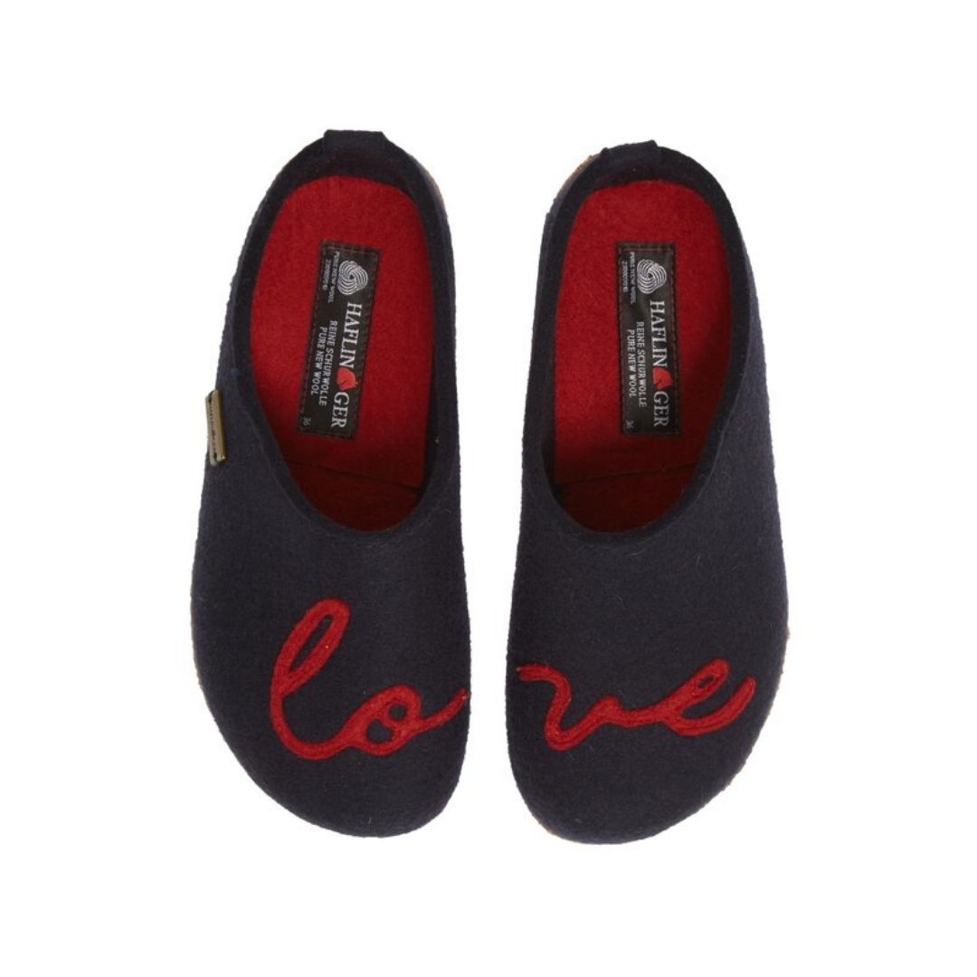A pair of navy wool slippers with word love across them. Grey footbeds have Haflinger logo on heels.
