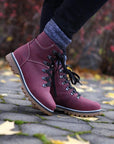Person wearing Martino branded burgundy leather ankle boots with black laces.