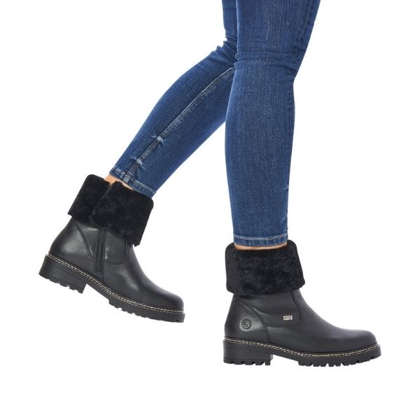 Women in jeans wearing black leather winter boot with fur cuff