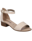 Off white sandal that has ankle strap with gold buckle and low stacked heel.