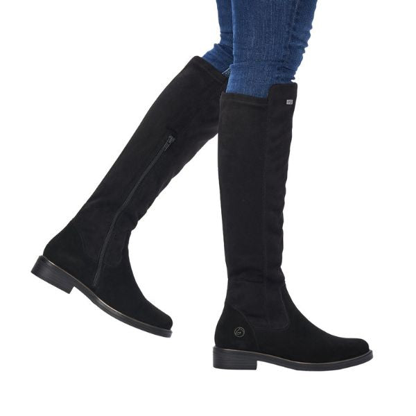 Legs in jeans wearing black tall boot with inside zipper and small silver Remonte emblem at top.