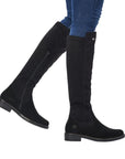 Legs in jeans wearing black tall boot with inside zipper and small silver Remonte emblem at top.