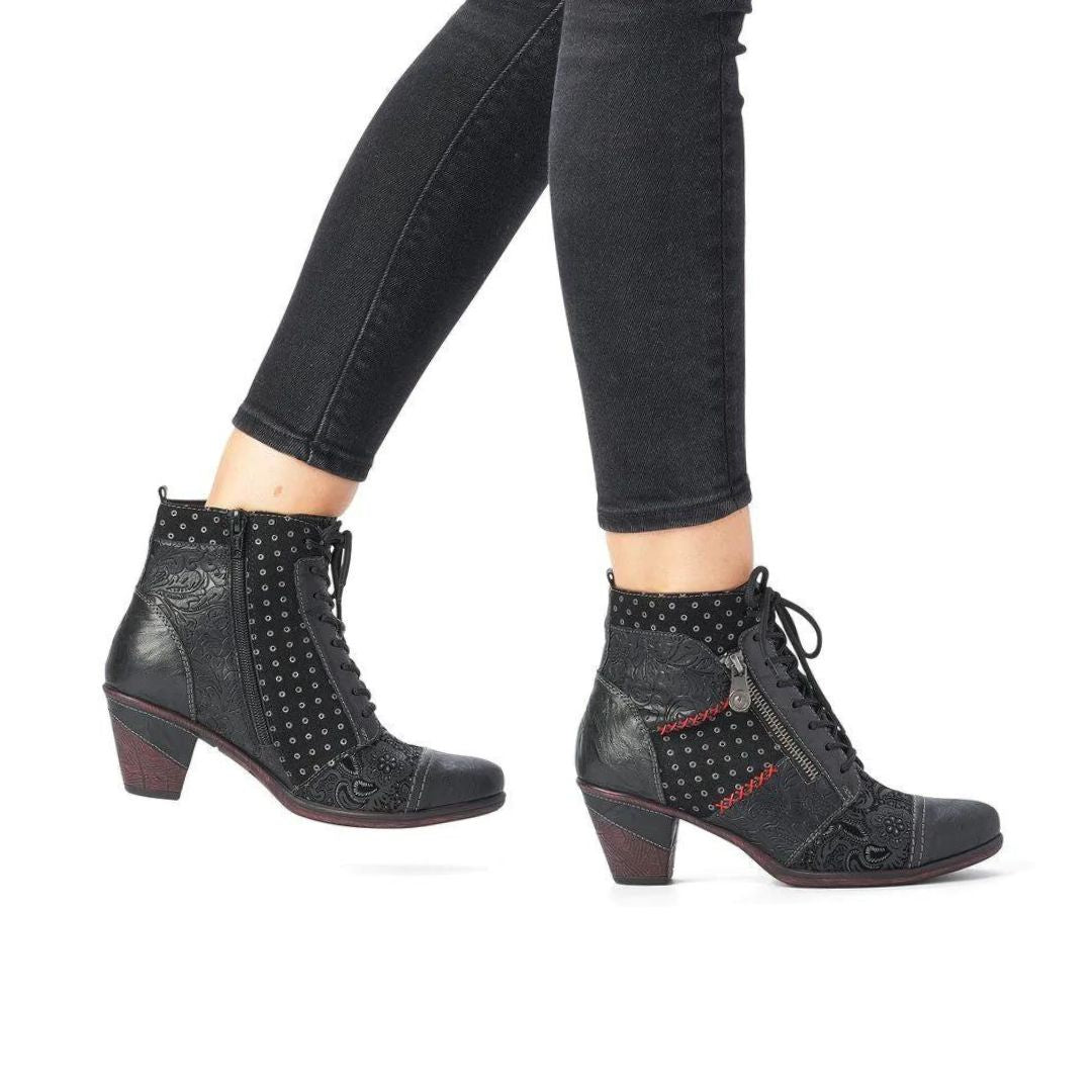 Legas in black jeans wearing black heeled booties with laces, decorative zipper and paisley and polka dot details.