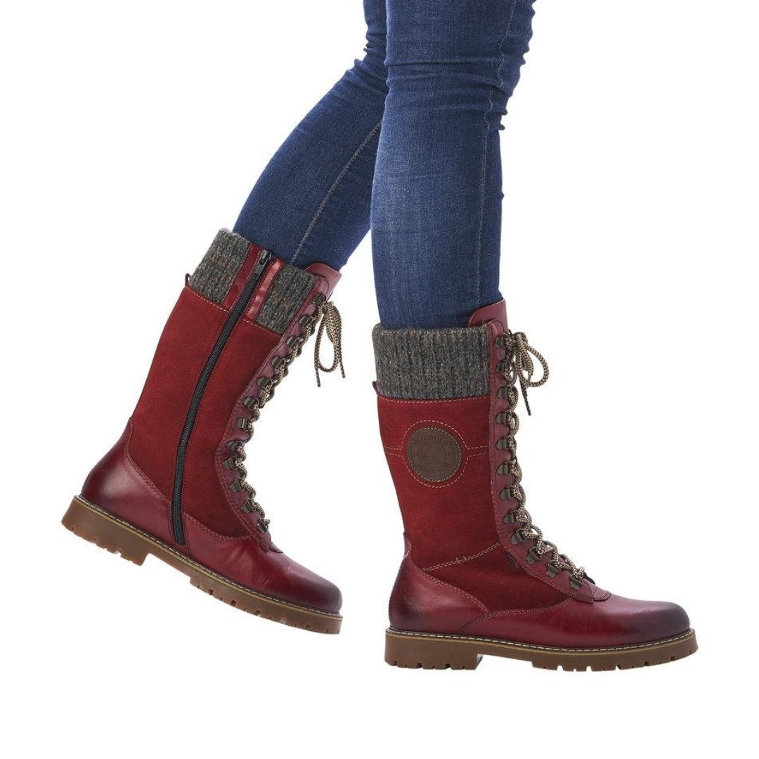 Women in jeans wearing mid-calf red winter boot with laces and inside zipper.