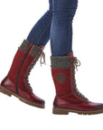 Women in jeans wearing mid-calf red winter boot with laces and inside zipper.