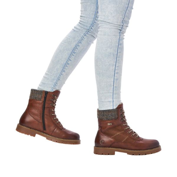 Women in light coloured jeans wearing brown lace up winter boot with inside zipper
