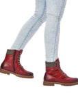 Women wearing jeans and  red mid winter boots with laces and side zipper.